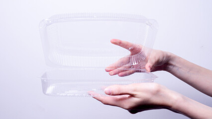female hand holding transparent plastic packaging on gray background