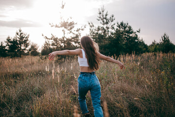 Fototapeta na wymiar A Free, Happy Woman Enjoying Nature. Pretty Girl Outdoors. The girl runs across the field