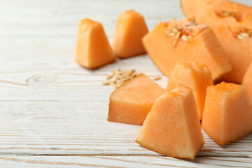 Ripe melon slices on white wooden background