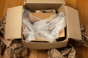 Cardboard boxes and crumpled wrapping paper with bubble wrap on the wooden floor of the room