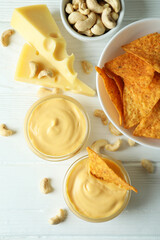 Snacks with cheese sauce on white wooden table