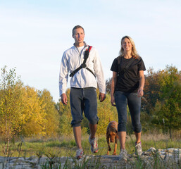 Junges Paar mit Hund beim Wandern in herbstlicher Natur