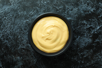 Bowl with cheese sauce on black smokey background