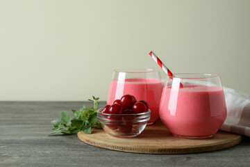 Glasses of cherry smoothie and ingredients on gray textured table