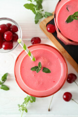 Glasses of cherry smoothie and ingredients on white wooden table