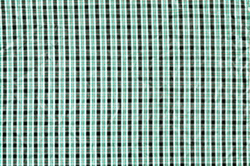 The texture of a cotton fabric in a small cage is green and black. The background is simple, but a pleasant color of the fabric.