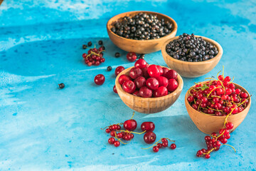 Fresh organic summer berries mix on blue concrete  background. Blueberries, red black currant and cherries. Top view. Concept of summer food. Flat lay, copy space