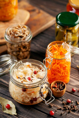 Fermented preserved vegetables food concept. Glass jars with fermented, pickled and canned vegetables  on  kitchen table. Conservation of farm organic seasonal harvest. Healthy homemade food