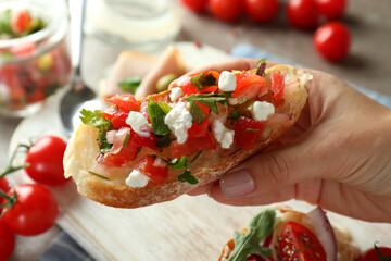 Female hand holds bruschetta, close up and selective focus