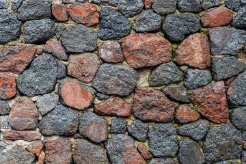 Texture. Stones of gray-blue and red-brown shades are fastened with cement.