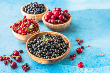 Fresh organic summer berries mix on blue concrete  background. Blueberries, red black currant and cherries. Top view. Concept of summer food. Flat lay, copy space