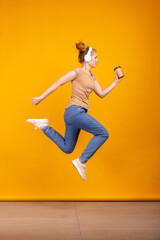 Fototapeta na wymiar Vertical portrait of young active girl jumping isolated on yellow studio background. Concept of human emotions, facial expression, youth, sales, ad.