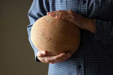 Woman in shirt holds basket with melon