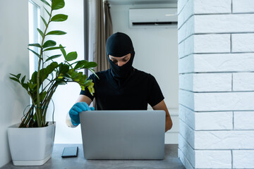 hacker in black balaclava on a laptop
