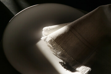 Piatto bianco vuoto e tovagliolo in cotone; composizione su fondo nero