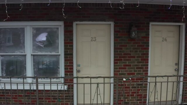 A pull away shot of a door, of motel room number 23, revealing a second floor balcony and the other surrounding units.