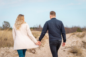 A young couple walking on sand dunes.In the distance, the forest.Adventure travel lifestyle concept.