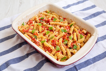 Homemade Baked Feta Tomato Pasta in a baking dish on a white wooden background, side view.