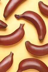Tasty red baby bananas on yellow background, flat lay