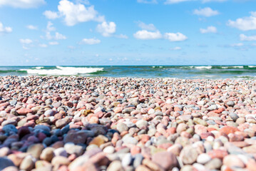 Fototapeta na wymiar Small pebbles on the shore. sunny summer day blue sky,white clouds. beautiful lonely pebble beach.Copy space.