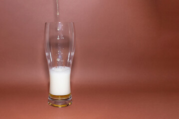 Last drops beer pouring from bottle into glass.Frothy and amber brilliance craft beer,Dark brown...