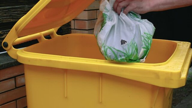 A man throws a bag of trash into a waste container. Sorting non-degradable waste garbage. Recycling. Ecology.