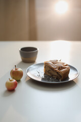 Breakfast with homemade apple cake and a cup of coffee on white table in a sunny morning