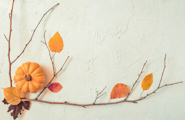 Halloween grunge white holiday background, pumpkins, dry branches and orange leaves decorations. Autumn light frame composition, party invitation card, flat lay, copy space.