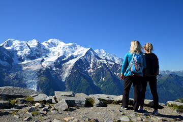 Hikers looking at the Mont Blanc from the summit of Le Brevent. French Alps, Chamonix, France.