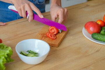 Close-up woman hands chopping cucumber vegetables by knife