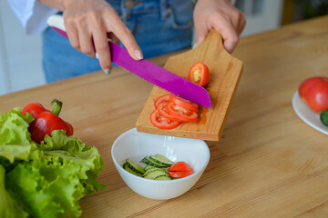 Close-up woman hands chopping cucumber vegetables by knife