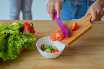 Close-up woman hands chopping cucumber vegetables by knife