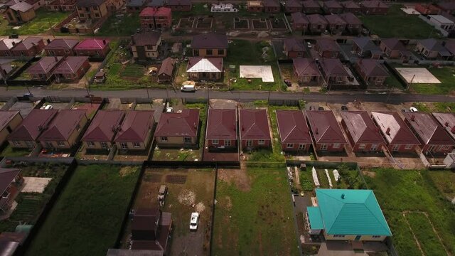Aerial view. Many private houses in the field at summer cloudy day. Private sector development concept. Construction of one-story houses. Aerial drone from above view.