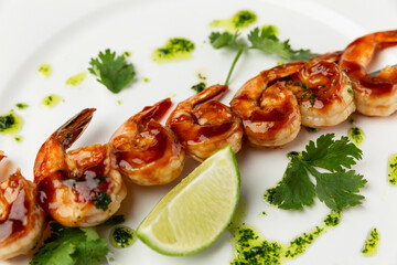 Fried shrimps with sauce and lime on a white plate. Appetizing dietary snack. Close-up.