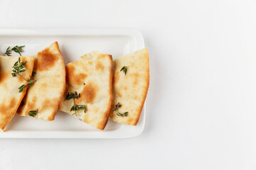 Traditional Italian bread with rosemary. Appetizing slices on a white plate. White background. Space for text. Close-up.