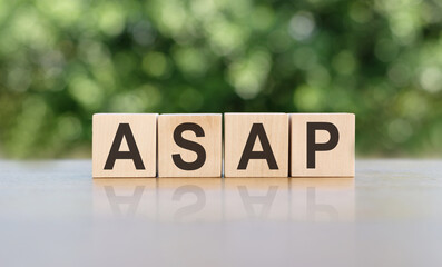ASAP - word written on wooden blocks. The text is written in black letters and is reflected in the mirror surface of the table. Business concept for your design.