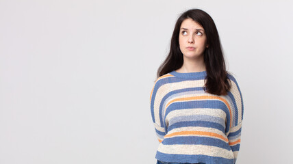 pretty woman with a worried, confused, clueless expression, looking up to copy space, doubting