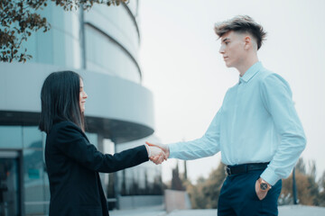 Apreton de manos firme de trabajo entre hombre joven empresario y mujer directiva detras del edificio de trabajo