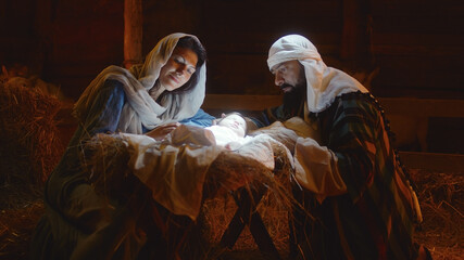 Mary and Joseph caressing baby Jesus in illuminated manger