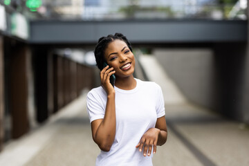 Portrait of beautiful young woman walking outdoors and calling by phone