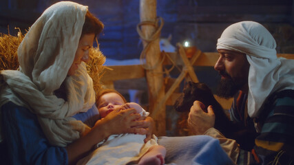 Joseph with lamb and Mary with baby Jesus in stable