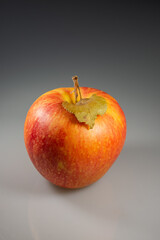 Pink apple with dry leaf.