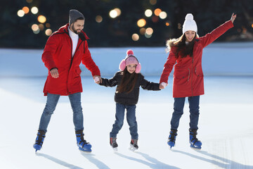 Happy family spending time together at outdoor ice skating rink - obrazy, fototapety, plakaty