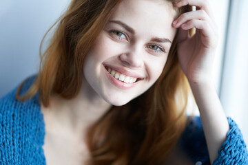 Fototapeta premium woman sitting on the windowsill with a blue plaid dreamy look