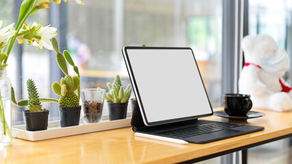 Smart tablet blank screen mockup on wooden desk, blurred window glass in the background