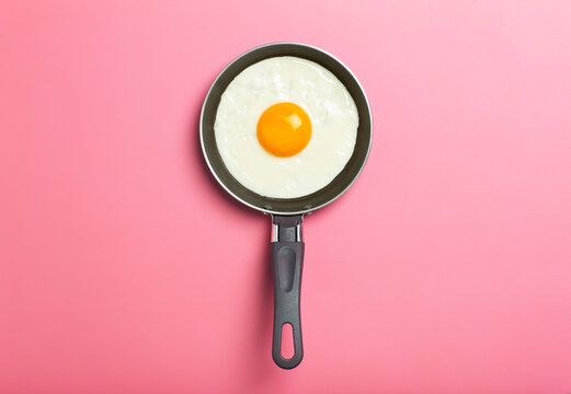Fried egg is minimal. Fried egg in a frying pan on an empty pink background. Creative breakfast and food idea.