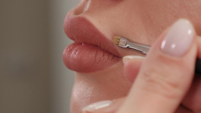 Close-up of a cosmetologist painting lips with a pencil before permanent makeup. The cosmetologist is preparing for the permanent makeup procedure.