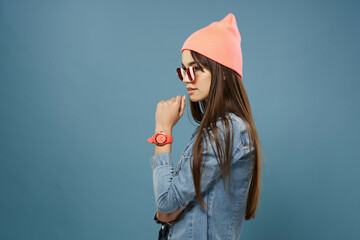 woman in pink hat sunglasses denim jacket hipster blue background