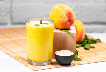 Smoothie with peach and mint leaf with piece of cloth on white brick background, Healthy summer diet