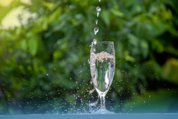 Glass of water on a wooden bar. There was water droplets scattered on the floor.